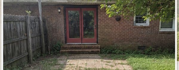 The back of a brick ranch house with concrete steps and an overgrown patio — before a walk-out deck was added